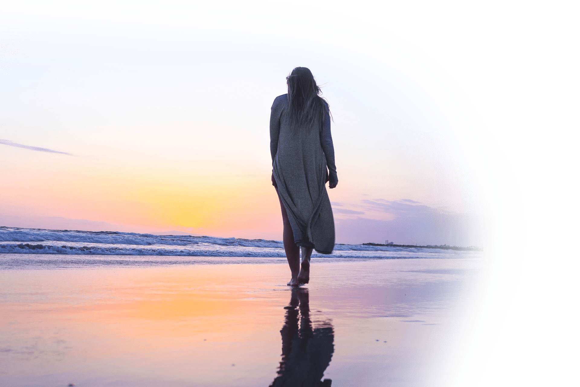 Image of woman walking on a beach during a sunset