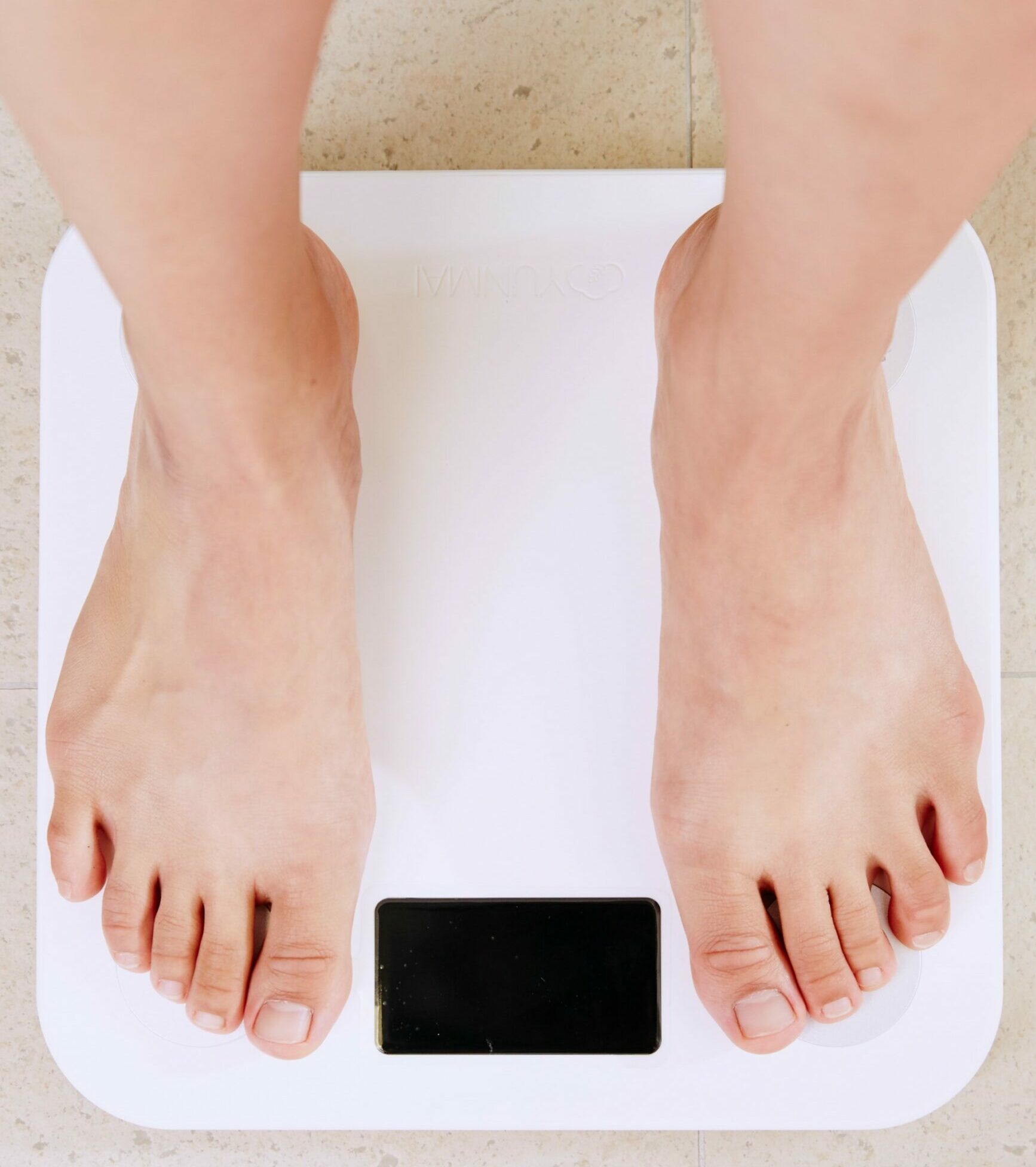 Image of an individual measuring their weight with a scale