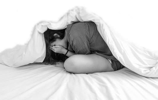 Woman hiding in bed out of fear.